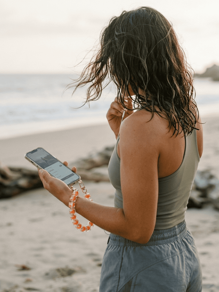 Frau mit Handykette Cubes am Strand