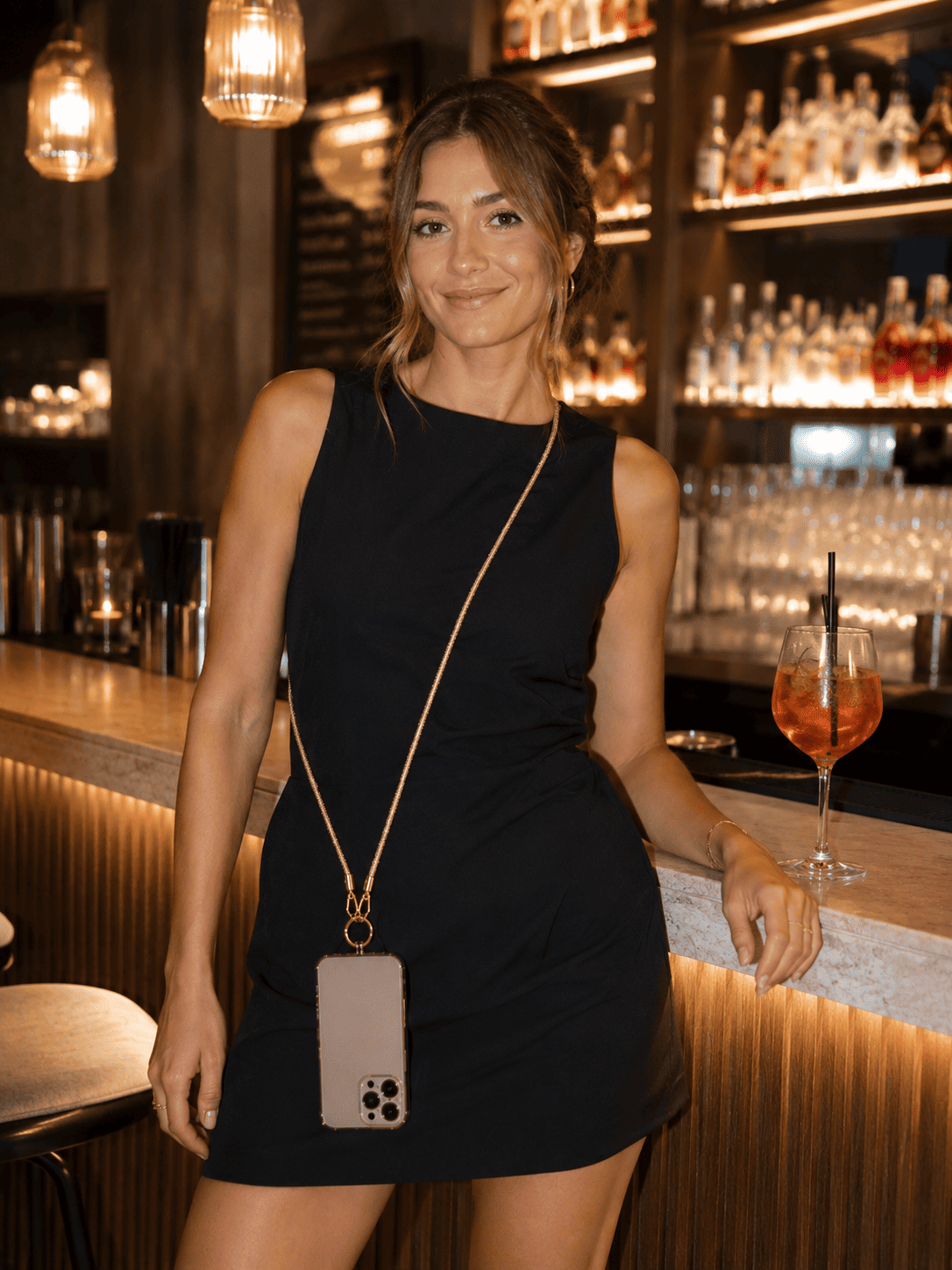 Glitzernde Handykette an Frau in Bar mit iphone